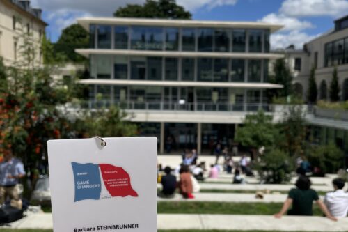 Eine Kongress Namensschild Karte. Im Hintergrund eine Platzsituation mit einem Gebäude.