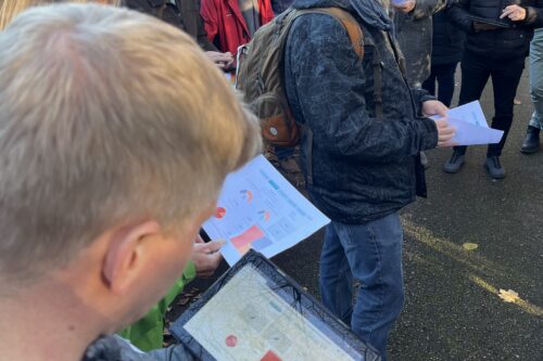 Mehrere Menschen schauen auf ein Tablet und Papieren mit Infografiken