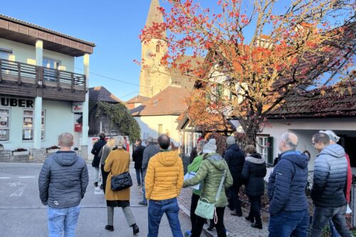 Eine Gruppe spaziert eine Sztaße entlang. Im Hintergrund eine Kirche.