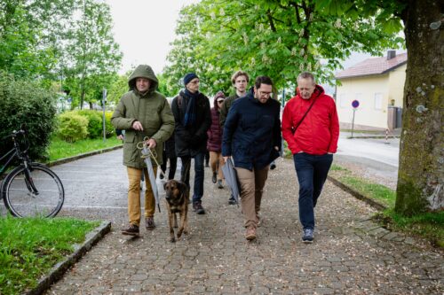 Eine Gruppe von Personen beim Spazierengehen. Eine Person führt einen Hund an der Leine.