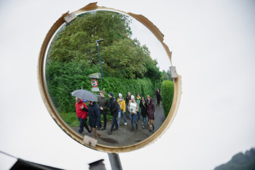 Ein Verkehrsspiegel, in dem sich eine Personengruppe spiegelt.