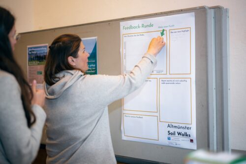 Eine Person schreibt auf ein Plakat, auf dem "Feedback" steht.